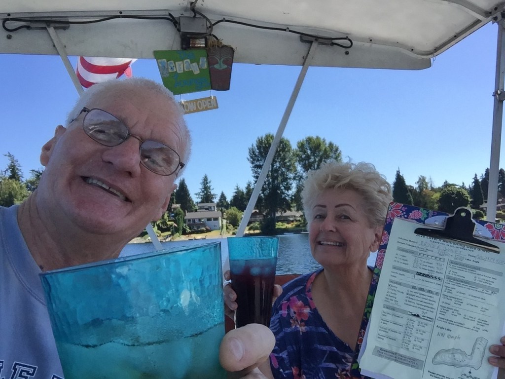 A man and a woman in a boat holding cold drinks and their lake sampling data form